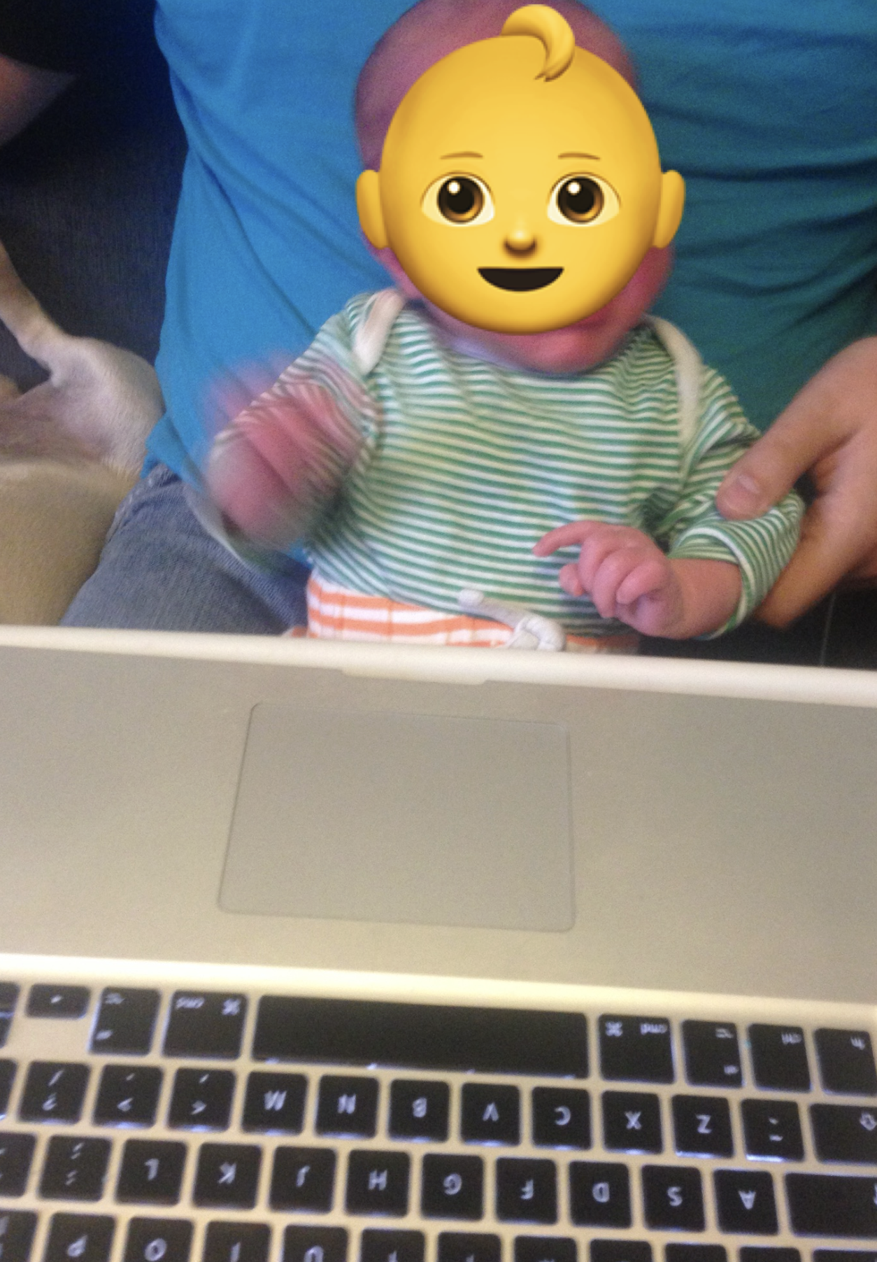 A newborn baby crying with a laptop in the foreground
